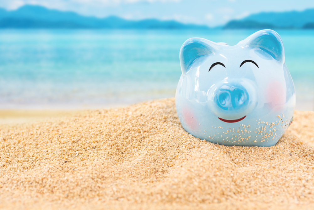 Summer,Happy,Piggy,Bank,On,Sand,Beach,Over,Blurred,Tropical